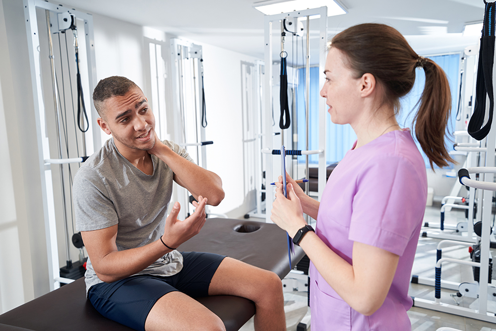 African American man talking with doctor in physical therapy clinic